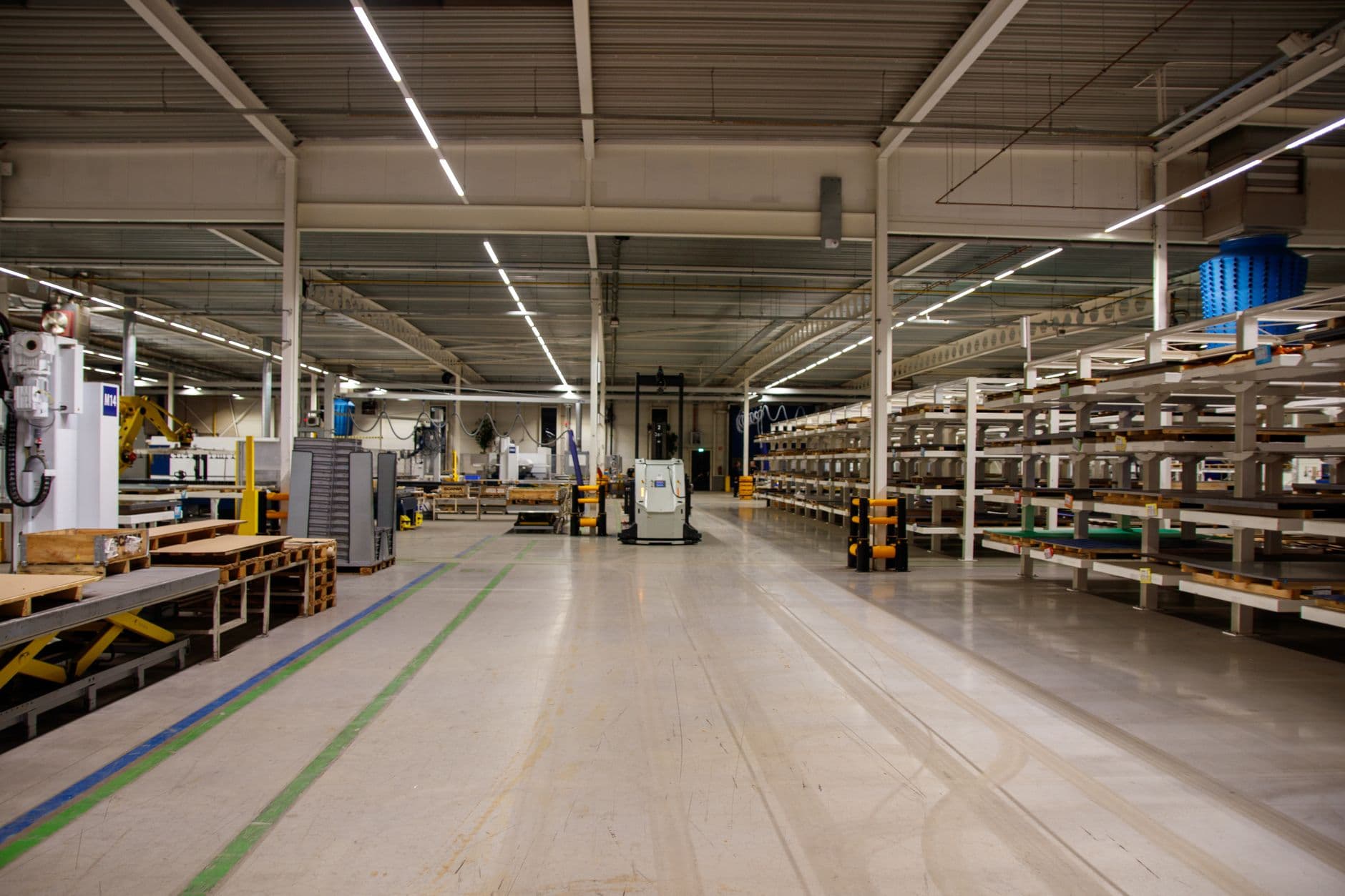 Spacious industrial warehouse interior featuring machinery and storage shelves.