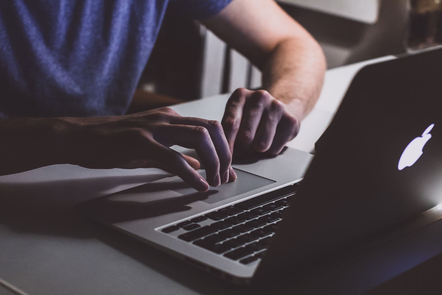 Close-up of hands typing on a laptop in a dark office setting. Perfect for business and technology themes.