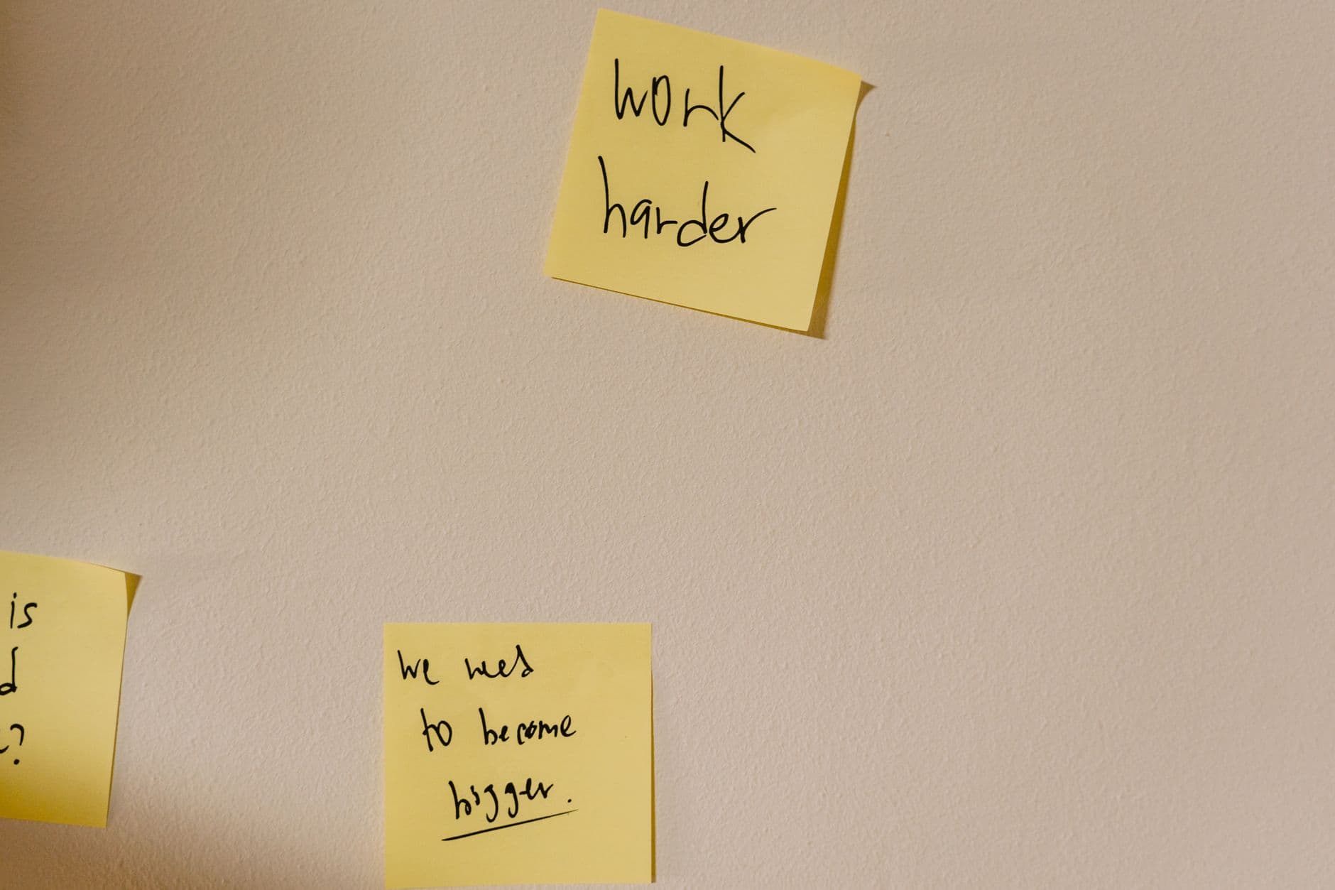 Yellow sticky notes with motivational phrases posted on a white wall, inspiring action.
